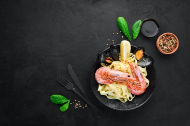 Bir tabak içinde deniz ürünleri ve limon ile makarna. Karides, midye. Eski arka planda. Üst görünüm. Metniniz için boş alan.