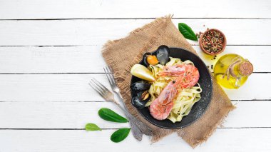 Bir tabak içinde deniz ürünleri ve limon ile makarna. Karides, midye. Eski arka planda. Üst görünüm. Metniniz için boş alan.