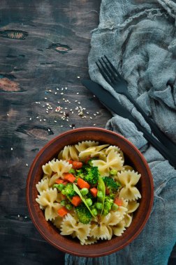 Tabak üzerinde sebze ile farfalle makarna. Üst görünüm. Siyah bir arka planda. Ücretsiz kopya alanı.