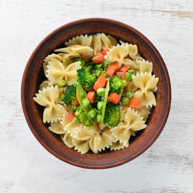 Tabak üzerinde sebze ile farfalle makarna. Üst görünüm. Siyah bir arka planda. Ücretsiz kopya alanı.