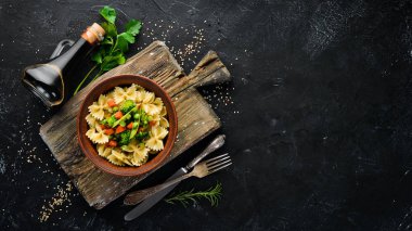 Tabak üzerinde sebze ile farfalle makarna. Üst görünüm. Siyah bir arka planda. Ücretsiz kopya alanı.
