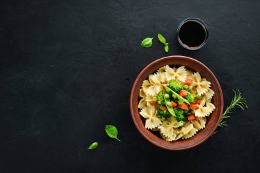 Tabak üzerinde sebze ile farfalle makarna. Üst görünüm. Siyah bir arka planda. Ücretsiz kopya alanı.