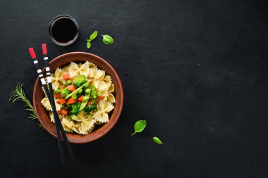 Tabak üzerinde sebze ile farfalle makarna. Üst görünüm. Siyah bir arka planda. Ücretsiz kopya alanı.