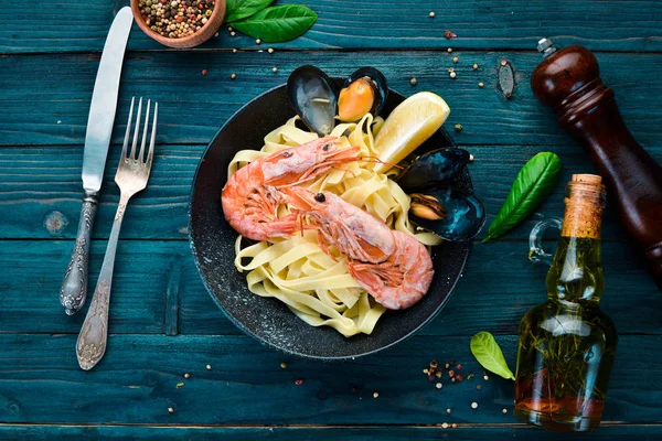 Bir tabak içinde deniz ürünleri ve limon ile makarna. Karides, midye. Eski arka planda. Üst görünüm. Metniniz için boş alan.