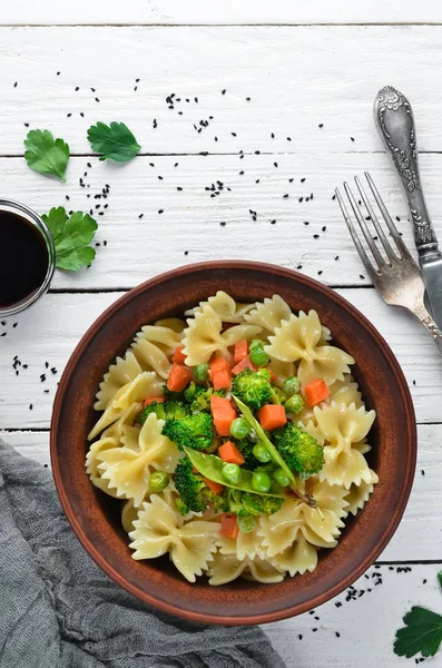 Tabak üzerinde sebze ile farfalle makarna. Üst görünüm. Siyah bir arka planda. Ücretsiz kopya alanı.