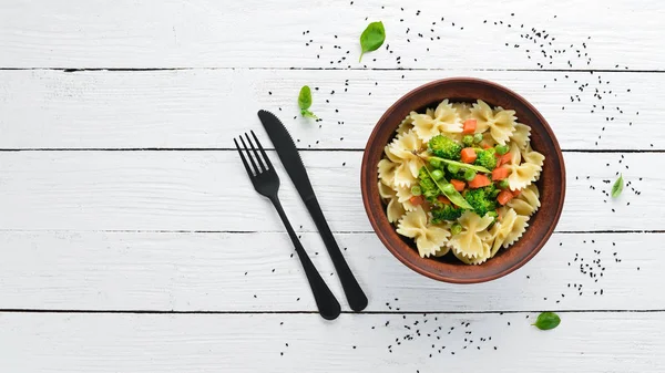 Tabak üzerinde sebze ile farfalle makarna. Üst görünüm. Siyah bir arka planda. Ücretsiz kopya alanı.