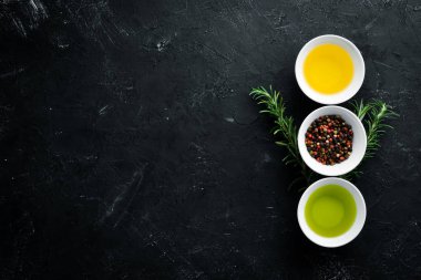 Zeytin yağı, ayçiçeği yağı ve biberiye. Siyah taş arka planda. Üst görünüm. Ücretsiz kopya alanı.
