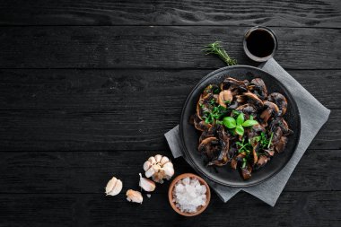 Tabak üzerinde maydanoz ile kızarmış mantar. Siyah bir arka planda. Üst görünüm. Metniniz için boş alan.