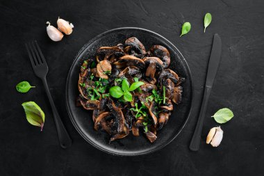 Tabak üzerinde maydanoz ile kızarmış mantar. Siyah bir arka planda. Üst görünüm. Metniniz için boş alan.