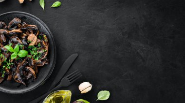 Tabak üzerinde maydanoz ile kızarmış mantar. Siyah bir arka planda. Üst görünüm. Metniniz için boş alan.