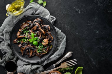 Tabak üzerinde maydanoz ile kızarmış mantar. Siyah bir arka planda. Üst görünüm. Metniniz için boş alan.