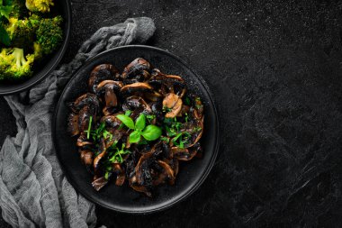 Tabak üzerinde maydanoz ile kızarmış mantar. Siyah bir arka planda. Üst görünüm. Metniniz için boş alan.