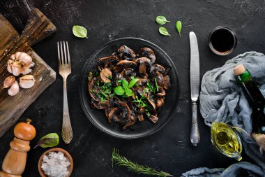 Tabak üzerinde maydanoz ile kızarmış mantar. Siyah bir arka planda. Üst görünüm. Metniniz için boş alan.