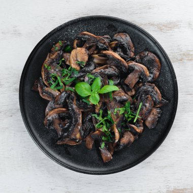 Tabak üzerinde maydanoz ile kızarmış mantar. Siyah bir arka planda. Üst görünüm. Metniniz için boş alan.