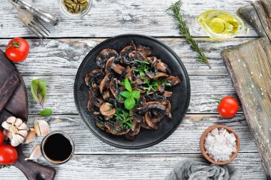 Tabak üzerinde maydanoz ile kızarmış mantar. Siyah bir arka planda. Üst görünüm. Metniniz için boş alan.