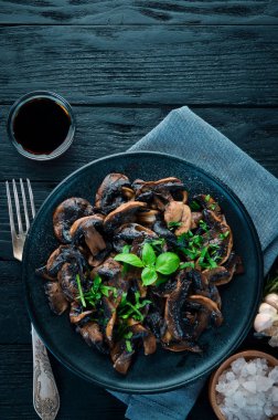 Tabak üzerinde maydanoz ile kızarmış mantar. Siyah bir arka planda. Üst görünüm. Metniniz için boş alan.