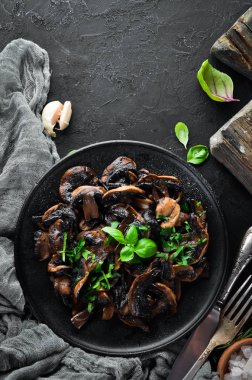 Tabak üzerinde maydanoz ile kızarmış mantar. Siyah bir arka planda. Üst görünüm. Metniniz için boş alan.