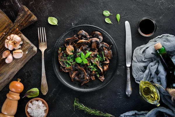 Tabak üzerinde maydanoz ile kızarmış mantar. Siyah bir arka planda. Üst görünüm. Metniniz için boş alan.