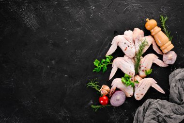 Çiğ tavuk kanatları. Siyah taş arka planda. Üst görünüm. Ücretsiz kopya alanı.