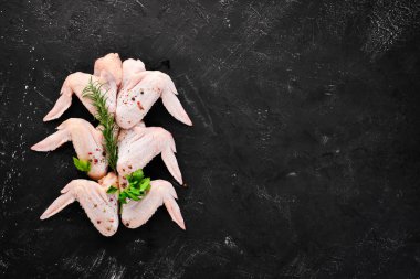 Çiğ tavuk kanatları. Siyah taş arka planda. Üst görünüm. Ücretsiz kopya alanı.