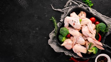 Çiğ tavuk kanatları. Siyah taş arka planda. Üst görünüm. Ücretsiz kopya alanı.