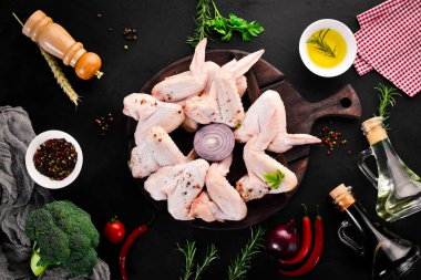 Çiğ tavuk kanatları. Siyah taş arka planda. Üst görünüm. Ücretsiz kopya alanı.