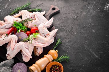 Çiğ tavuk kanatları. Siyah taş arka planda. Üst görünüm. Ücretsiz kopya alanı.