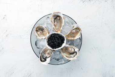 Bir tabak buz ve limonda istiridye ve siyah havyar. Deniz ürünleri. Üst te. Ücretsiz kopyalama alanı.