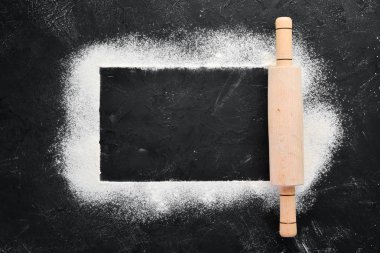 Pişirme nin arka planı. siyah bir arka plan üzerinde oklava ve un. Üst te. Ücretsiz kopyalama alanı.