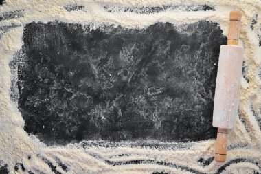 Pişirme nin arka planı. siyah bir arka plan üzerinde oklava ve un. Üst te. Ücretsiz kopyalama alanı.