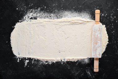 Pişirme nin arka planı. siyah bir arka plan üzerinde oklava ve un. Üst te. Ücretsiz kopyalama alanı.