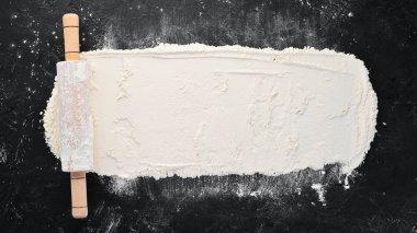 Pişirme nin arka planı. siyah bir arka plan üzerinde oklava ve un. Üst te. Ücretsiz kopyalama alanı.