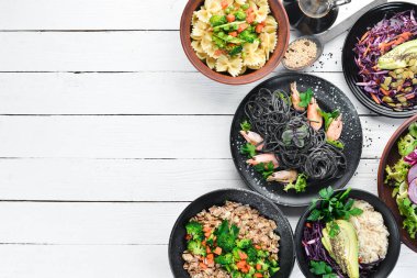 Yemek geçmişi. Makarna, pirinç, risotto, salata. Beyaz ahşap bir arka plan üzerinde. Ücretsiz kopyalama alanı.