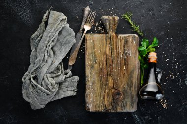 Wooden kitchen board and vegetables. On a black background. Free copy space.