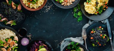 Bir dizi yemek ve tabak. Makarna, pirinç, risotto, salata. Siyah bir arka plan üzerinde. Ücretsiz kopyalama alanı.