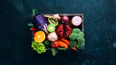 Siyah bir arka plan üzerinde ahşap bir kutu içinde taze sebze ve meyve. Organik gıda. Üst te. Ücretsiz kopyalama alanı.