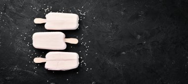 Beyaz çikolatalı bir sopanın üzerine dondurma. Siyah bir arka plan üzerinde. Üst te. Ücretsiz kopyalama alanı.