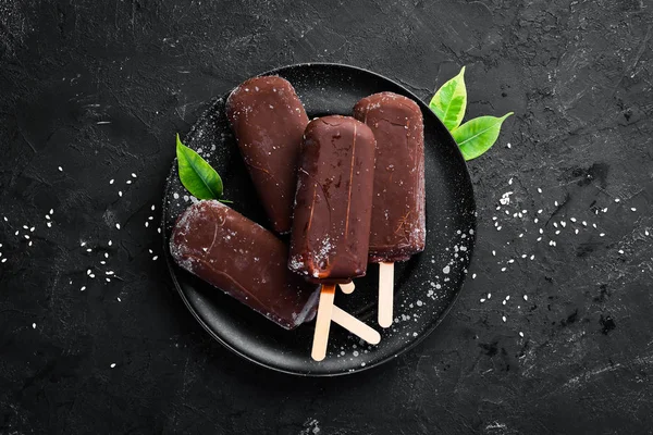 Chocolate ice cream on a stick. On a black background. Top view. Free copy space