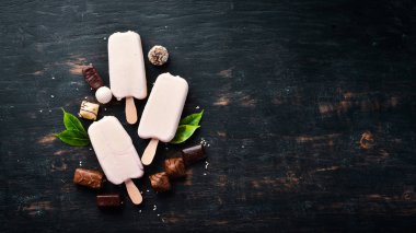 Beyaz çikolatalı bir sopanın üzerine dondurma. Siyah bir arka plan üzerinde. Üst te. Ücretsiz kopyalama alanı.