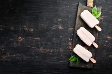 Beyaz çikolatalı bir sopanın üzerine dondurma. Siyah bir arka plan üzerinde. Üst te. Ücretsiz kopyalama alanı.