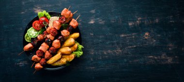 Siyah bir arka plan üzerinde patates ve sebze ile tavuk şiş kebap. Et. Üst te. Ücretsiz kopyalama alanı.