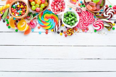 Beyaz ahşap arka plan üzerinde renkli şekerler, jöle ve marmelat. Tatlı. Üst te. ücretsiz kopyalama alanı.