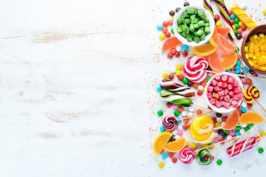 Beyaz ahşap arka plan üzerinde renkli şekerler, jöle ve marmelat. Tatlı. Üst te. ücretsiz kopyalama alanı.