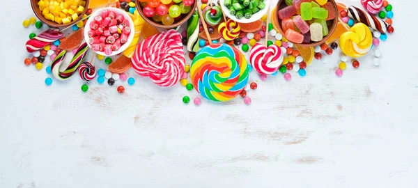 Beyaz ahşap arka plan üzerinde renkli şekerler, jöle ve marmelat. Tatlı. Üst te. ücretsiz kopyalama alanı.