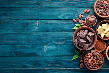 Mavi ahşap arka planda çikolata, kakao ve kakao çekirdekleri. Üst te. Ücretsiz kopyalama alanı.