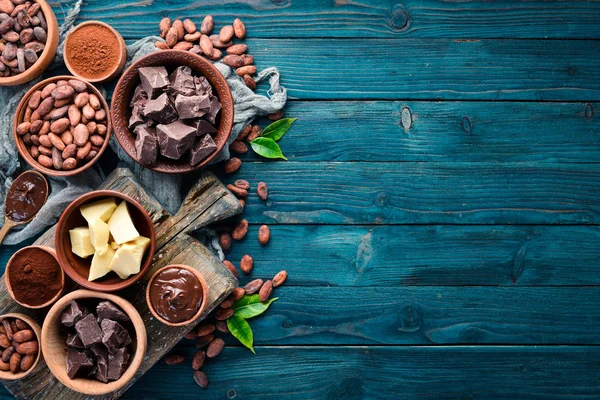 Chocolate, cocoa and cocoa beans on a blue wooden background. Top view. Free copy space.