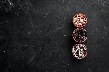 Renkli çiğ fasulye çeşitleri. Siyah taş bir masanın üzerinde. Üst te. Ücretsiz kopyalama alanı.