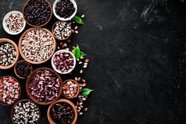 Renkli çiğ fasulye çeşitleri. Siyah taş bir masanın üzerinde. Üst te. Ücretsiz kopyalama alanı.