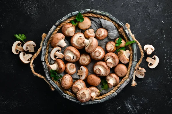 Mushrooms in a wooden box on the old table. Champignons Top view. Free copy space.