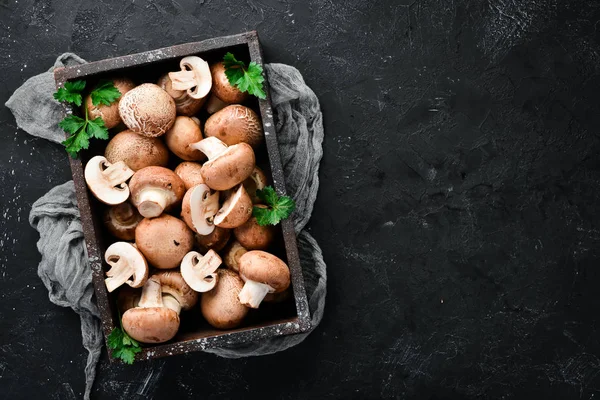 Mushrooms in a wooden box on the old table. Champignons Top view. Free copy space.